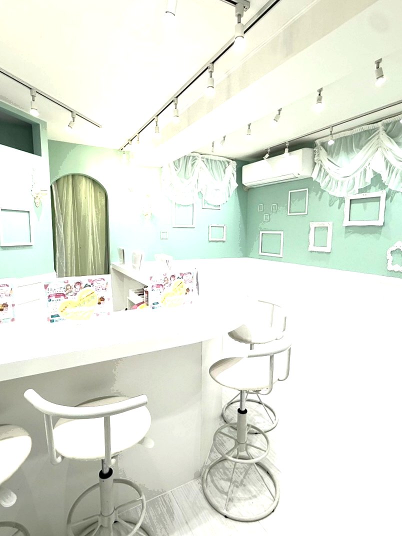 虹色fairies cafe の店内、ミントグリーンの壁に白いフレームが並ぶフォトスポット